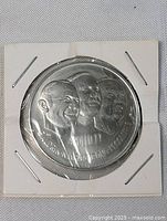 Front view of the Apollo moon landing commemorative coin sealed in protective packaging showing embossed astronaut portraits and inscriptions.