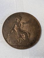 Full view of copper-toned 1912 English penny coin showing Britannia seated design and date.
