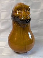 Front and angled views of the monkey head Majolica pottery water pitcher showing glossy lead glaze and facial details.