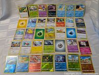 Photo of 32 assorted Pokémon cards spread out, showing both holo and non-holo cards with various Pokémon characters and energy cards.