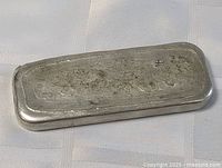 Top-down view of rectangular handmade pewter ingot bar showing textured surface and rounded edges.
