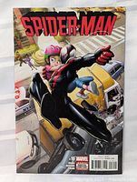 Front cover of Spider-Man comic book issue #16 showing Miles Morales Spider-Man carrying a child with city street scene background.