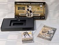 Box opened with pack of cards and a protective sleeve holding a Sidney Crosby card displayed.