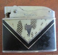 Front side of the lighter showing the Art Deco design with black, cream, and silver geometric patterns and brand name 'Hadson' engraved on the mechanism.