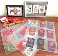 Overall group showing framed Shell Oil patch, framed animal textile silks, multiple small provincial fabric pennants and patches