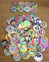 Full assortment of colorful vintage pogs and slammers spread out on a table showing skulls and vivid artwork.