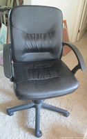 Front view of the black IKEA Moses office chair showing padded seat, backrest with channel tufting, and plastic armrests.