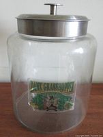 Photo showing large clear glass jar with aluminum lid and "Dank Grasshopper" label.