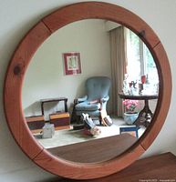 Full front view of the round pine frame mirror hanging on a wall, showing the room reflected in the glass.