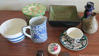 Photo showing full lot with pitcher, bowls, jars, cup with saucer, and pottery bottles