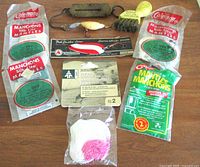 Full view of vintage fishing gear and camping lantern mantles lot arranged on wood surface showing packages and loose items.
