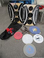 Full lot view with two bean bag toss boards, frisbees, horseshoes, and black bags