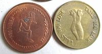 Close-up of two vintage token coins, one bronze with 'PROVIDER' text and embracing nude figures, the other brass-colored with nudes and 'ALLS YOU LOSE TAILS YOU WIN' text.
