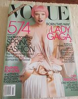 Cover photo of the Vogue magazine showing Lady Gaga in a pale pink dress and short pink hair. The cover highlights 574 pages of spring fashion and various editorial topics.