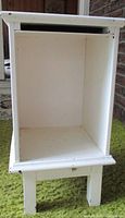 Front angle view of vintage white side table cabinet showing open storage compartment inside and wear on edges.