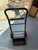 Aluminum hand truck dolly, side view showing yellow frame, black handle, platform plate, and wheels.