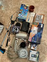 Full lot overview showing all included household items and accessories grouped on floor, including Light Angel LED light, Aqua Globes, Sony clock radio, APC battery backup, floor care kit, grabber tool and flower pot.