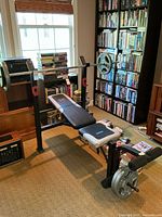 Full view of bench setup with barbell loaded on rack, weight plates on storage pegs, and Spot Pro arms attached