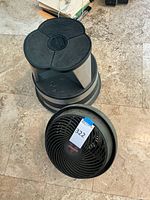 Black and silver rolling step stool showing three-lobed textured top platform and base.