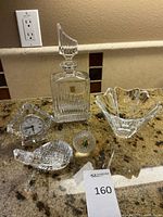 Full view of 5 crystal pieces on countertop including decanters, bowl, decorative balls, and clock.