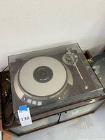 Turntable in clear dust cover on wood plinth with cables