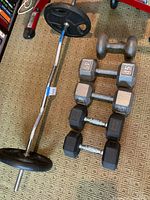 EZ curl bar loaded with two 25 lb plates alongside five dumbbells