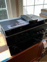 Three stacked audio components including Samsung DVD player on top, DSL Two surround processor in the middle, and Denon receiver at bottom with remote controls on top