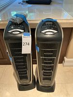 Photo showing two Lasko tower heaters side by side with control panels visible on top.