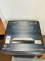 Photo of the LG LRY-517 DVD Recorder and VCR combo unit box showing front and top with branding and model info.