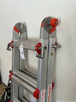 Side view of folded ladder with red lock mechanisms and brand markings.