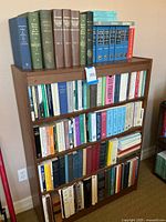 Full wooden bookshelf displaying all volumes on four shelves
