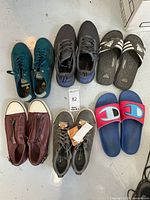 Photo showing six pairs of men's shoes including Adidas and Champion slide sandals, 2 lace-ups in blue and gray with tags, and maroon slip-on shoes.
