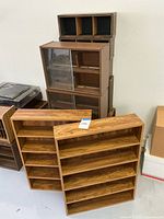 Wooden media storage cabinets and shelves stacked together, showing variety of shelving units including ones with sliding glass doors and open shelves.
