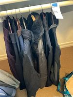 7 men's coats and jackets on hangers showing varied styles and colors including leather, knit and fleece
