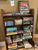 Image showing wooden bookshelf with multiple stacked PC game and software titles with visible spines showing various titles including Max Payne 3, Left 4 Dead, Portal 2, Mahjongg, and puzzle games.