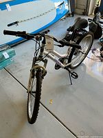 Front angle view of white Roadmaster women's mountain bike with knobby front tire and front suspension fork, showing handlebar and black seat.