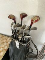Overview photo of set of golf clubs in black Spalding vinyl golf bag with yellow/gold trim, showing club heads and shafts extending from bag.