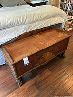 Full view of the top and front of the cedar chest showing brown wood with scratches and wear.
