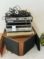 Stack of cables and remote controls atop Akai CR-80D-SS, RCA VCR and Pioneer LD-660 on speaker