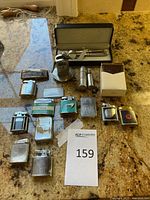 Full view of all 14 assorted lighters arranged on a countertop, various materials, designs, and brands visible.