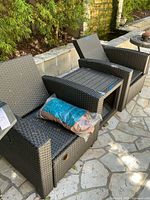 Wicker outdoor furniture set including chairs flanking the side table, illustrating scale and coordinated design.