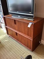 Front view showing two slatted‐front compartments with TV on top