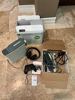 Xbox 360 console, controller, headset, cables, and box set on floor showing entire bundle setup.