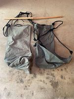 Two air chairs made of green and white striped fabric laid out with hanging straps and wooden rods on a hard surface.