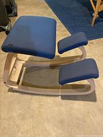 Full view of the kneeling chair showing blue cushions and wooden frame structure.