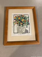 Framed artwork showing colorful nasturtiums and pansies in a vase, signed and dated 2014.
