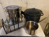 Photo showing bundle including stainless steel double boiler on rack, black speckled stock pot with lid, and a separate stainless steel pot on wooden surface.