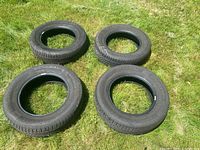 Four tires arranged on grass showing like new condition, tread visible
