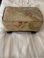 Top down view of rectangular footstool upholstered in floral chintz fabric on wooden legs