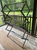 Front angle view of wooden drying rack, showing its expanding accordion frame and crossbars for drying clothes.